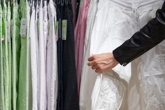 Shopper woman choosing clothes thinking looking at clothing while shopping in store. shopaholic woman chooses clothes in the store