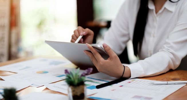 Close up of woman or accountant hand holding pen working on laptop computer for calculate business data, accountancy document and calculator at office, business concept.