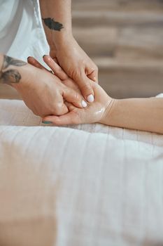 Professional confident massage master is doing procedures to caucasian woman in minimalistic modern cabinet