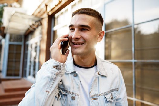 Young casual man walking on the city street and talking on the phone, close up portrait