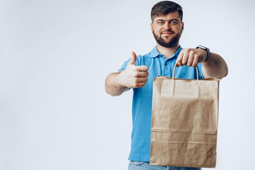 Delivery man with bag order from groceries on light grey background