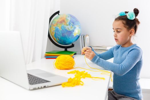 Girl knitting at home on a laptop online, distance learning