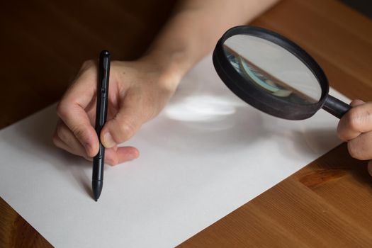 very aged person is writing on a paper with Magnifier