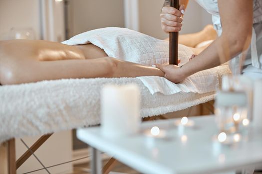 Professional confident massage master is doing procedures to caucasian woman in minimalistic modern cabinet