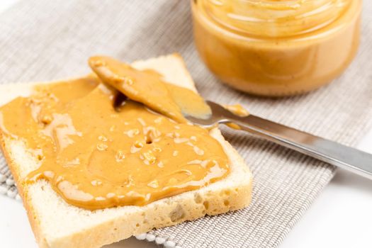 Crunchy peanut butter spreading on a toast, close up