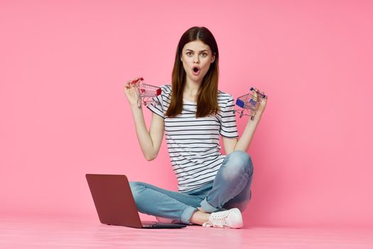 woman with laptop sitting on floor technology internet shopping pink background. High quality photo