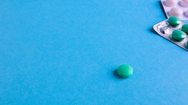 Two packs of pills and one round pill to the side on a blue background with copy space. antiviral tablets for pneumonia and bacterial infection. medicines and wellness treatments