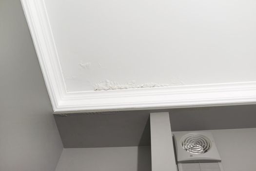 Large spots and cracks on the bathroom ceiling after flooding.