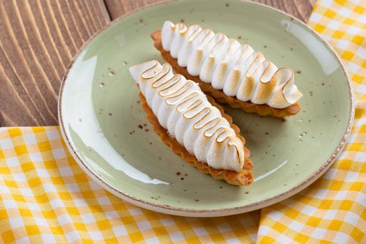 Lemon tart with meringue on green plate close up