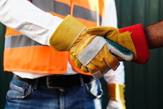 Close up photo photo of two men builders in workwear shaking hands