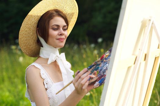 Woman in white dress artist paints on nature palette creative. High quality photo