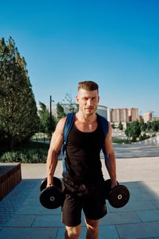 athletic man with dumbbells in his hands in the park training lifestyle. High quality photo