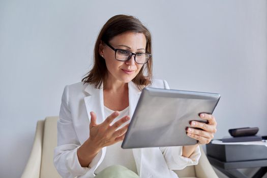 Talking businesswoman looking at screen of digital tablet. Middle aged business female using video call, for communication, remote work. Education, business, technology, corporate, telecommunications