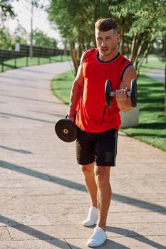 athletic man with dumbbells in his hands outdoors in the park. High quality photo