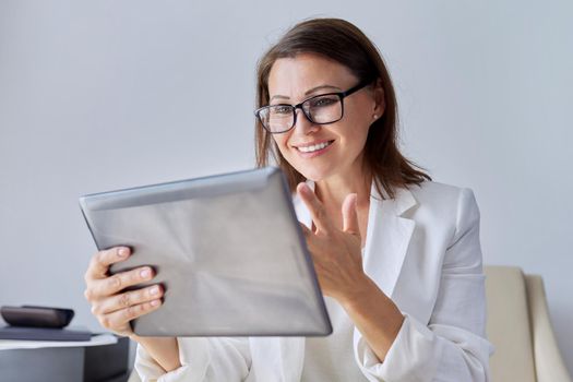 Talking businesswoman looking at screen of digital tablet. Middle aged business female using video call, for communication, remote work. Education, business, technology, corporate, telecommunications
