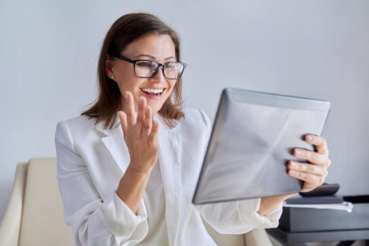 Talking businesswoman looking at screen of digital tablet. Middle aged business female using video call, for communication, remote work. Education, business, technology, corporate, telecommunications