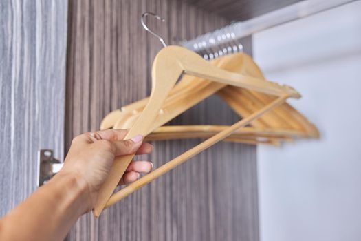 Wooden hangers in an empty open cabinet, hand taking a hanger. Clothing, fashion, shopping, new home, wardrobe organization concept