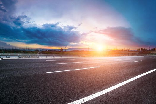 Asphalt road High way Empty curved road clouds and sky at sunset