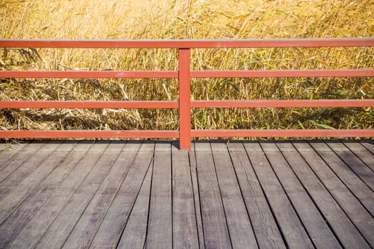 Detail of railing of an old rusty rural wood path through a reed field with a whishful and hopeful look