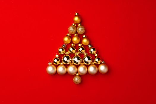 Christmas tree made of gold baubles on red background top view
