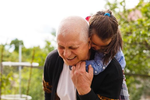 Funny lifestyle portrait of grandchild embracing grandfather