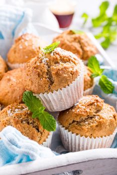 Delicious homemade coconut cinnamon muffins and mint leafs on old white tray. Healthy food concept.