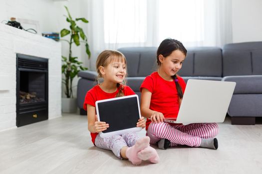 Little girls playing on a tablet computing device sitting on the floor