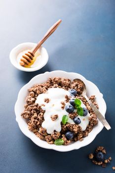 Homemade chocolate granola or muesli with yogurt and fresh blueberries for healthy morning breakfast, selective focus. Healthy food background with copy space for text.