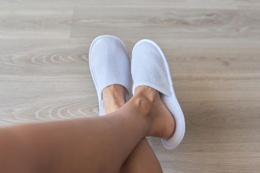 Close-up of woman's feet in white disposable hotel slippers.