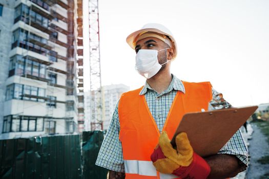 Foreman at work on construction site checking his notes on clipboard, close up