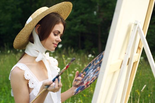 woman with a palette of paints painting a picture outdoors close-up. High quality photo