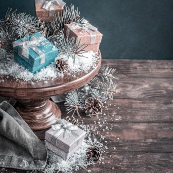 Christmas presents and decoration on wooden cake stand. Retro style toned christmas greeting card. With copy space for text.