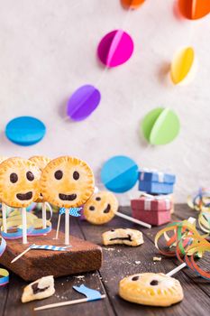 Homemade shortbread smiley cookies with dark chocolate on stick called pie pops. Childrens party background.