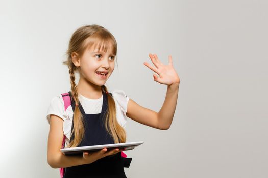 The little girl using the tablet on the white wall background