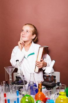 Thoughtful schoolgirl standing near blackboard in the laboratory classes in chemistry