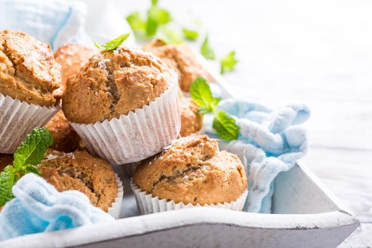 Delicious homemade coconut cinnamon muffins and mint leafs on old white tray. Healthy food concept with copy space.