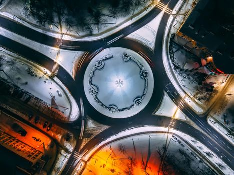 Aerial view of roundabout road with circular cars in small european city at winter night, long exposure. Kyiv region, Ukraine
