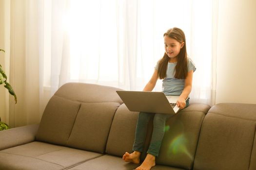 Remote lessons. The child smiles happily and gets knowledge remotely. Little girl study online learning from home with laptop. Online school.