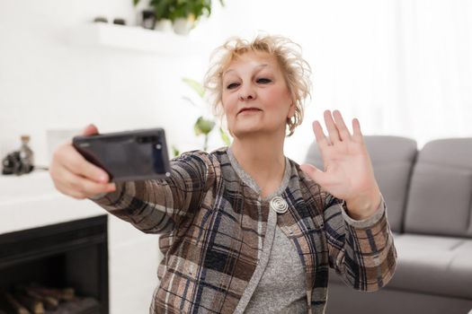 elderly woman using touch screen mobile for taking selfie or making video call