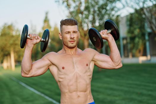 sporty man with pumped up body in park workout exercise. High quality photo