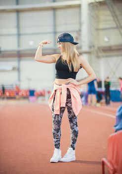 Young fit athletic woman showing her arm muscles. Full height