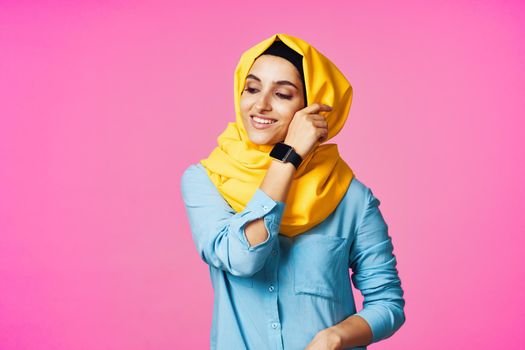 woman wearing yellow hijab electronic watch technology pink background. High quality photo