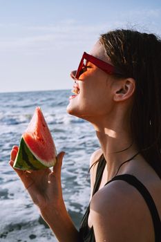 woman in black swimsuit with watermelon by the ocean. High quality photo