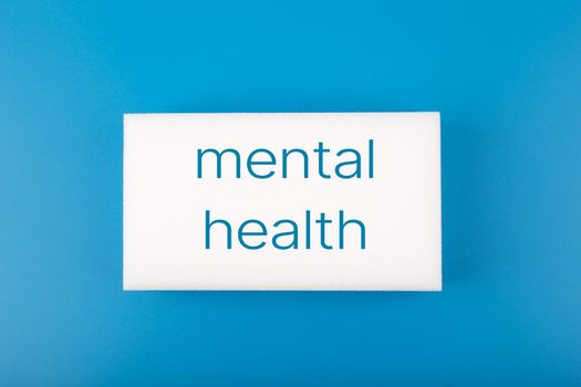 Minimal simple flat lay with white rectangle with written mental health text on dark blue blue background. Concept of world mental health day, mental health assessment and awareness