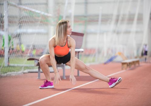 Young fit athletic woman stretching and preparing to run. Mid shot