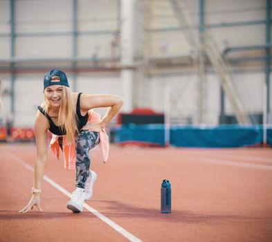 Young fit athletic woman warming up. Looking in the camera. Mid shot