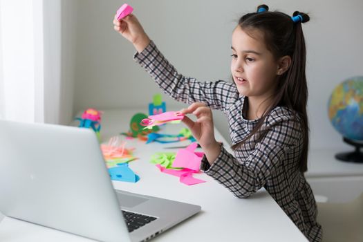 Beautiful little girl cutting paper with scissors on the art lesson class. Children education concept. Kids crafts.Back to schoo