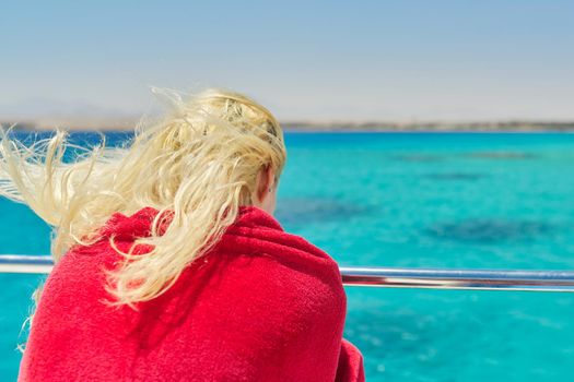 Young blonde female on yacht looking at turquoise coral reefs in Red Sea. Tourism, nature, travel, diving, snorkeling, water world concept, copy space