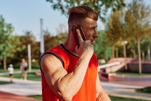 athletic man talking on the phone in the park. High quality photo