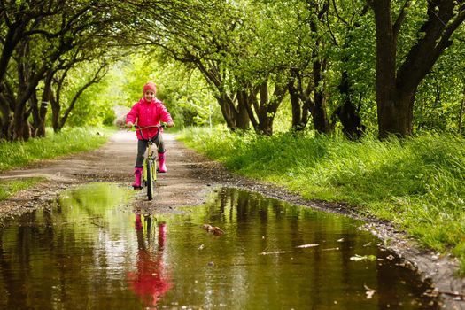 little girl riding bike in water puddle